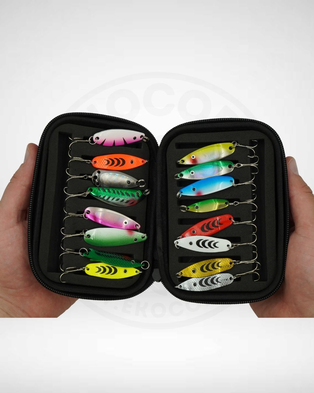 Set of colorful fishing lures in a black case held by hands on a white background