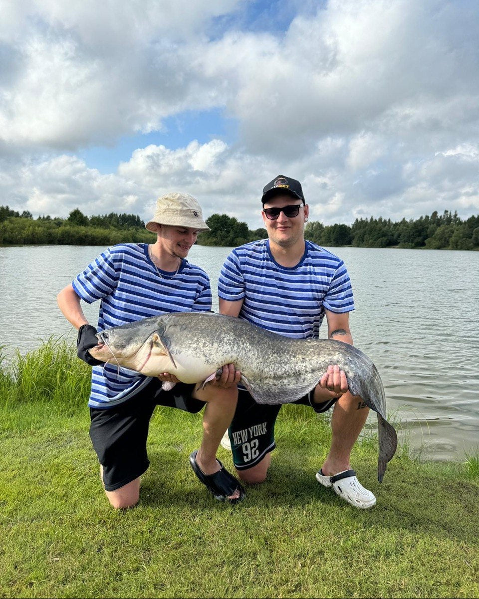Ekocope owners holding a large fish by a lake
